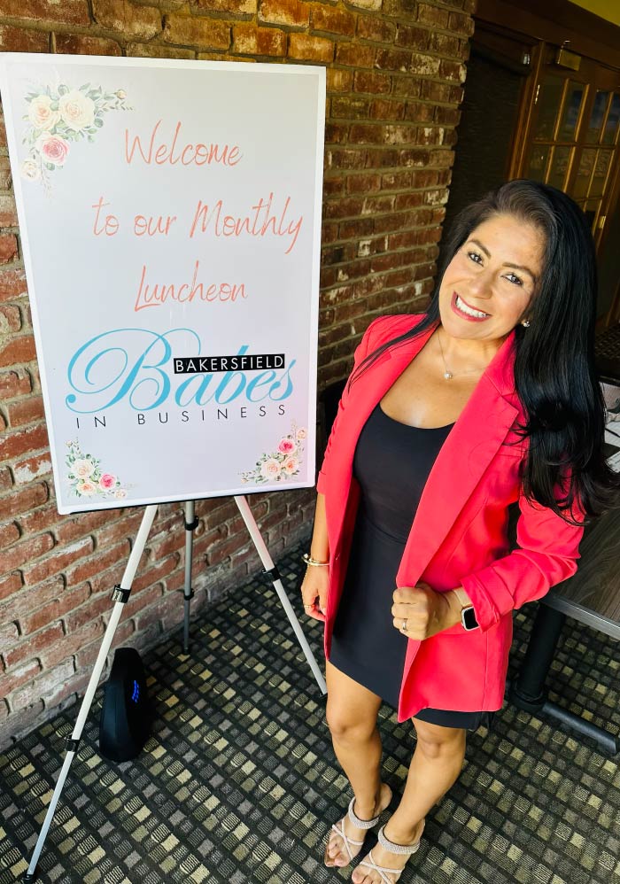 Karol Oxford, Principal HR Consultant, standing beside a "Bakersfield Babes in Business" welcome sign, reflecting the firm's active engagement in local networking and professional community leadership.